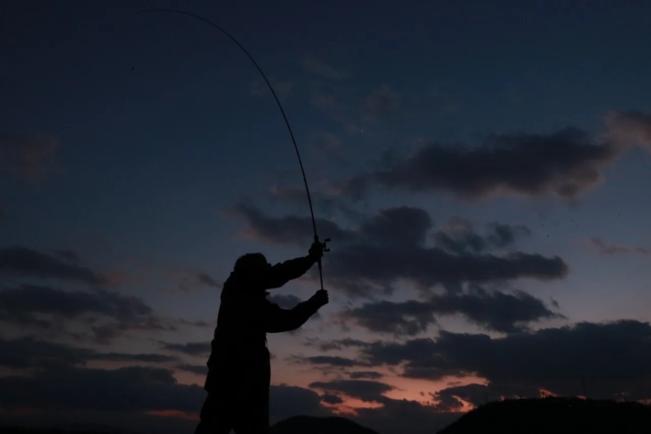 夕暮れの中で竿を振るシルエット