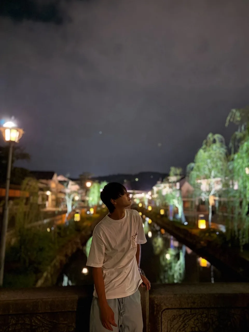 夜の川沿いで景色を見上げる石川ハルト